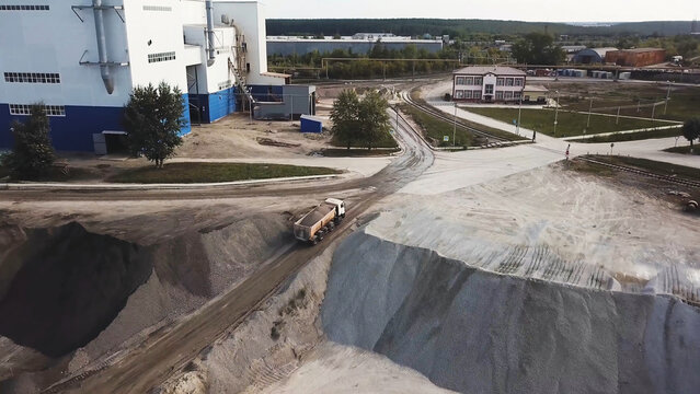 Aerial top view of quarry during work hours. Stock footage. Industrial background with sand quarry and a loaded lorry driving to the factory, professional equipment and machinery.
