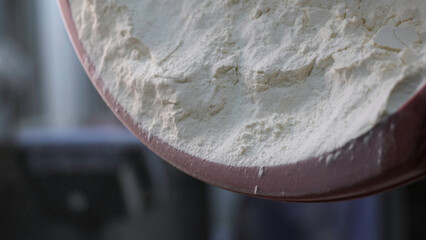Close up for white flour being put to the iron bowl at the bakery, bread products concept. Stock footage. White flour falling down from the plastic bowl.