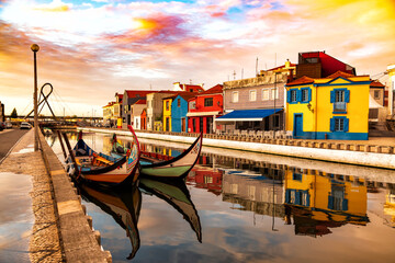 Aveiro, Portugal, Traditional colorful Moliceiro boats docked in the water canal among historical buildings.