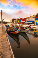 Fototapeta na wymiar Aveiro, Portugal, Traditional colorful Moliceiro boats docked in the water canal among historical buildings.