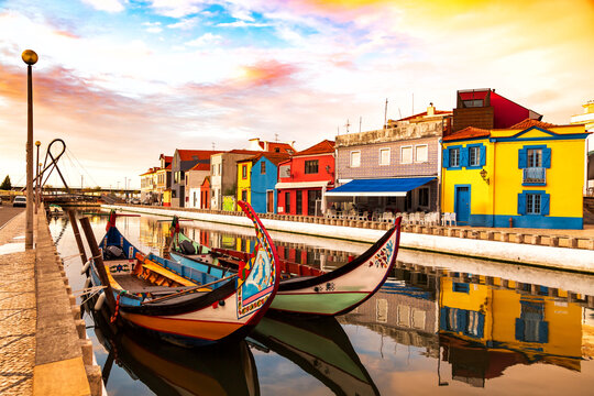 Aveiro, Portugal, Traditional colorful Moliceiro boats docked in the water canal among historical buildings.