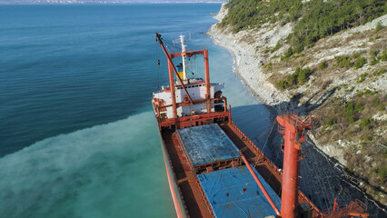 Aerial top view of an empty, red barge moored near the beautiful blue sea shore. Big Industrial...