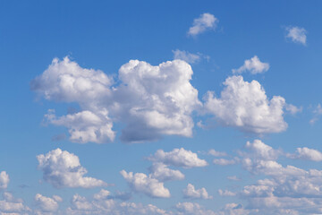 Blue cloudy sky with many beautiful white fluffy cumulus clouds in sunlight background texture