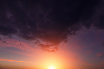 Epic dramatic sunset, sunrise on storm sky with dark clouds, orange yellow sun and sunlight