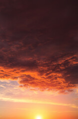 Epic dramatic sunset, sunrise on storm sky with dark clouds, orange yellow red sun and sunlight
