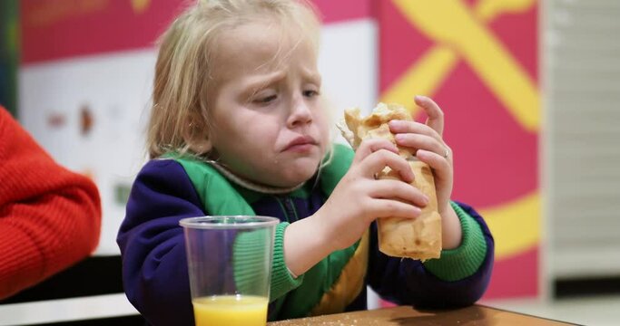 Kid eating hot dog with orange juice