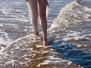 sea waves and feet of a walking woman