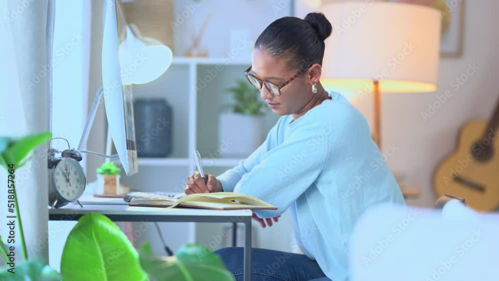 Aufkleber Market research analyst witing and taking notes in a diary while working remote at a desk at home. One young, serious black female researcher planning and organizing her online schedule and calendar