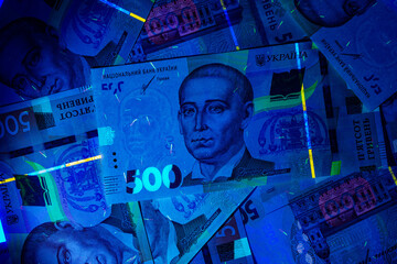 Ukrainian currency hryvnia in ultraviolet rays. The beam of the UV flashlight on the Banknotes of...
