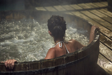 Portrait of a young woman relaxing in a hot tub at night
