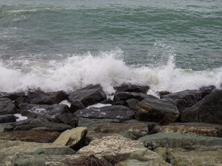 Fototapeta premium Rocky seashore. The shore is fortified with huge stones. Large waves on the pier. Big wave. Windy weather