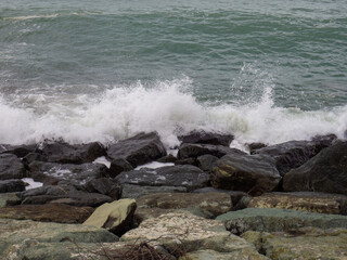 Fototapeta na wymiar Rocky seashore. The shore is fortified with huge stones. Large waves on the pier. Big wave. Windy weather