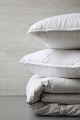 Fototapeta na wymiar Soft folded blanket and pillows on light grey table, closeup