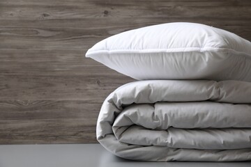 Soft folded blanket and pillow on light grey table, closeup