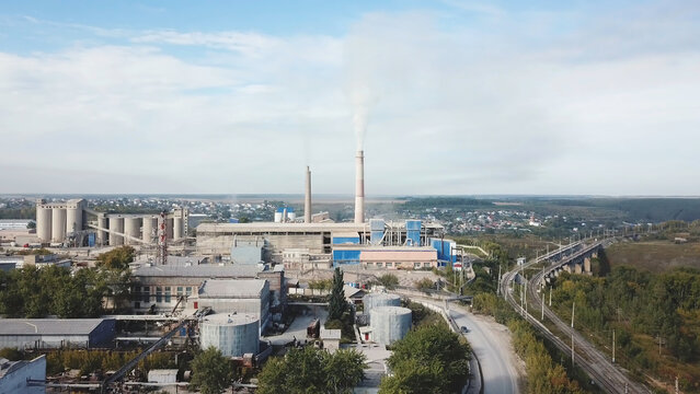 Aerial view of power plant generating heat and electricity on blue cloudy sky background. Stock footage. Visible high pipes with smoke, industrial landscape.