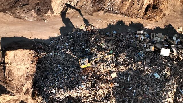 Landfill with Construction waste (CDW). Trash disposal for recycling and re-use. Excavator log grab crane on landfill. Recycling of Construction waste or debris. Secondary raw. Wood Waste Recycling.
