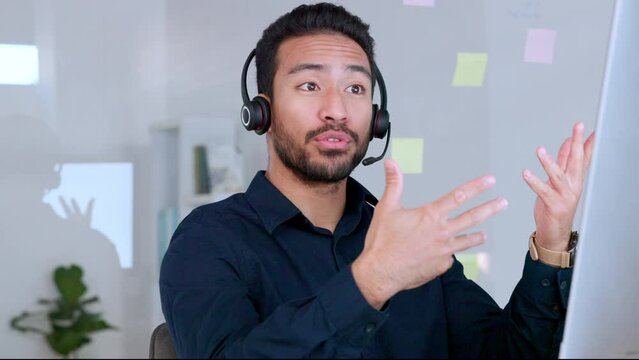 Male call center agent talking on headset and explaining product while working in an office. Confident and cheerful salesman looking at computer and giving advice for customer service and support