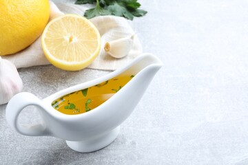 Ceramic boat with lemon sauce on light table, space for text. Delicious salad dressing