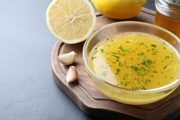 Bowl with lemon sauce and ingredients on dark table, space for text. Delicious salad dressing