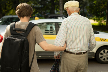 Grandpa gets in taxi. Grandson takes grandfather to car. Old man goes to transport. Assistance to pensioner.