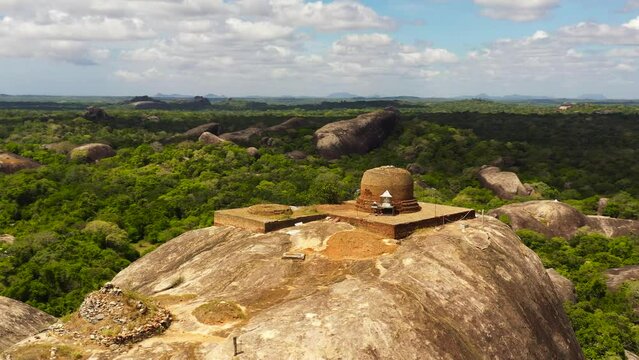 Aerial drone of Kudumbigala Monastery Complex and rainforest on a background of blue sky and clouds. Sri Lanka, Okanda.