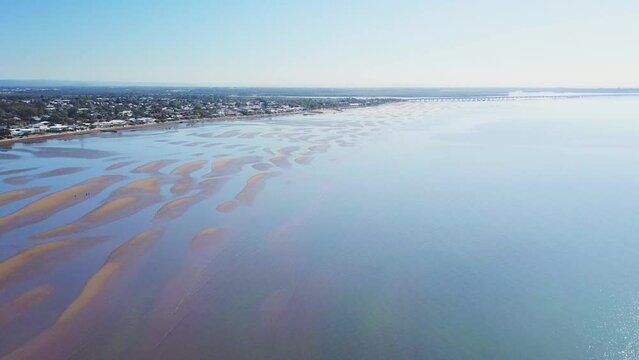 Populated coastal area at low tide with exposed sand flats, aerial