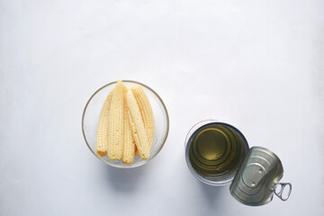  baby corn in a bowl with a empty can container on yellow background 