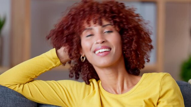 Flirty black woman blushing, rolling hair on fingers while on a date sitting on a sofa. Portrait of beautiful edgy girl face with curly afro looking at camera and smiling with a sensual piercing eyes