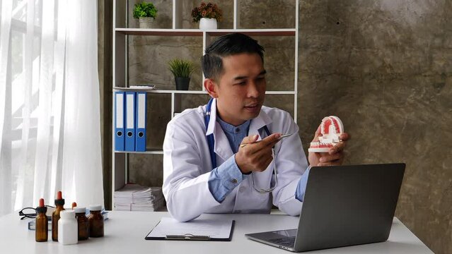 Online medical consultation. Asian people Male dentist communicating with his patient via internet connection.