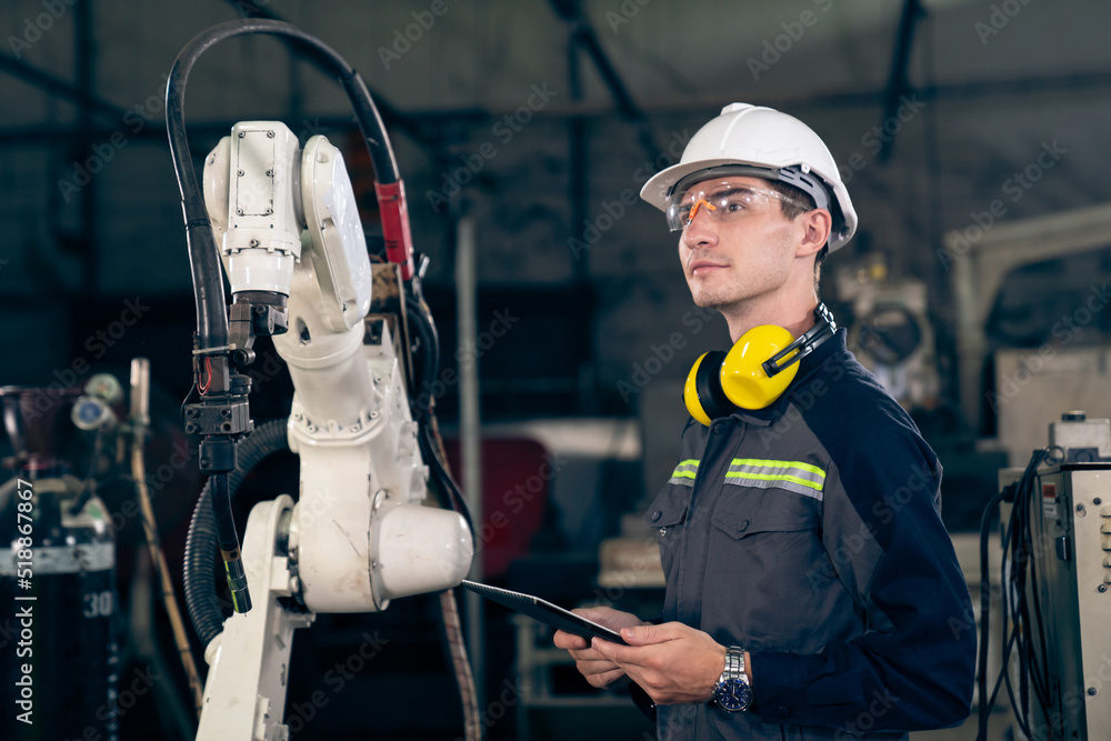 Poster young factory worker working with adept robotic arm in a workshop . industry robot programming softw