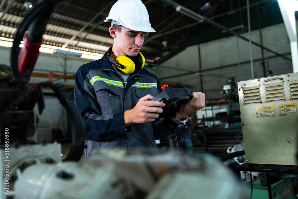 Poster young factory worker working with adept robotic arm in a workshop . industry robot programming softw
