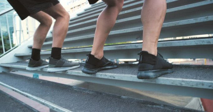 Closeup of the legs of athletes training and doing an outdoor workout on stairs in the city together. Two fit and sporty friends exercising and jumping on steps for fitness and health outside in town