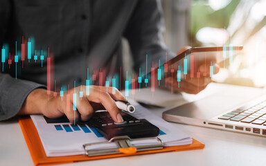 Business man working with tablet and using a calculator to calculate the numbers of static in...
