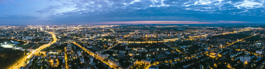Fototapeta na wymiar panoramic view of illuminated city streets and buildings after sunset. aerial view from flying drone.