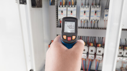an electrician is using a thermogun to analyze sub-wires and components, use digital infrared...