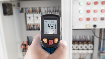 an electrician is using a thermogun to analyze sub-wires and components, use digital infrared...