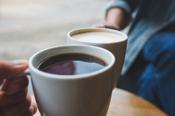 Closeup image of a couple people clinking coffee cups together in cafe
