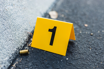 One yellow crime scene evidence marker on the street after a gun shooting brass bullet shell casing...