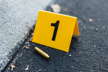 One yellow crime scene evidence marker on the street after a gun shooting brass bullet shell casing...