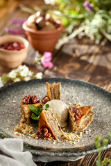 Traditional eastern sweets - baklava with walnuts and ice cream on wooden table. Turkish pastry baklava on modern plate in restaurant menu. Arabic dessert with nuts and honey on wooden background.