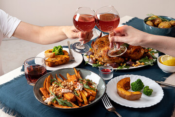 People celebrating Thanksgiving Day. Thanksgiving party table setting. Traditional holiday stuffed baked chicken dinner and vegetable. Family party or gathering.