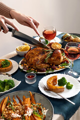 People celebrating Thanksgiving Day. Woman cutting meat for family and friends on table. Traditional holiday stuffed baked chicken dinner and vegetable. Family party or gathering.