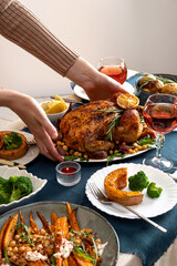 People celebrating Thanksgiving Day. Thanksgiving party table setting. Traditional holiday stuffed baked chicken dinner and vegetable. Family party or gathering.