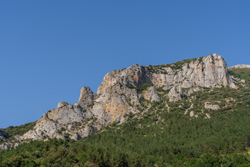 Scenic summer mountain landscape panorama of rocky outcrop emerging from forest in the Boulzane river valley near Salvezines, Aude, France