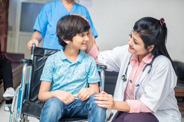 Indian doctor support disabled boy child patient sit on wheelchair at hospital, child healthcare concept.