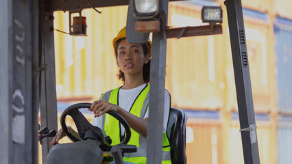 Young African American lady operates a forklift tractor to move containers around the shipyard....