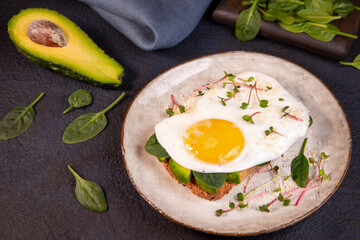 Sandwich with avocado, egg, spinach, microgreens and sesame. Healthy food rich in fiber, healthy fats, vitamins, trace elements.