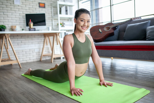 young asian woman working out and doing yoga in the cobra pose at home, healthy concept.