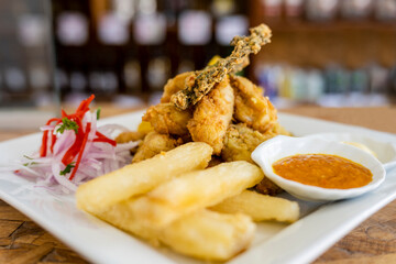 Peruvian food: chicharron de pescado or fish cracklings with fried cassava and onion salad with...