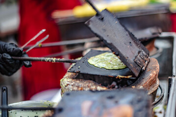 A vendor is making sweet Thong Muan desserts with iron sheet molds on a charcoal stove at Ban Chak Ngaew Chinese Community Market, Thailand.